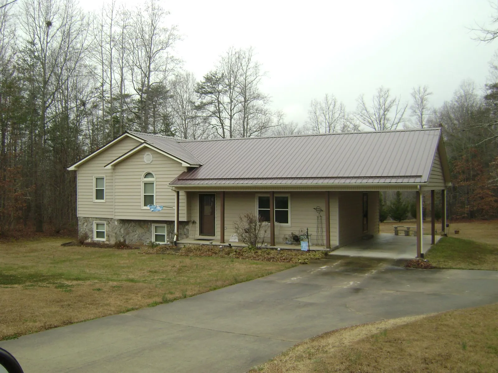Brown metal roof on a tan split level home with an attached carport in Huntsville